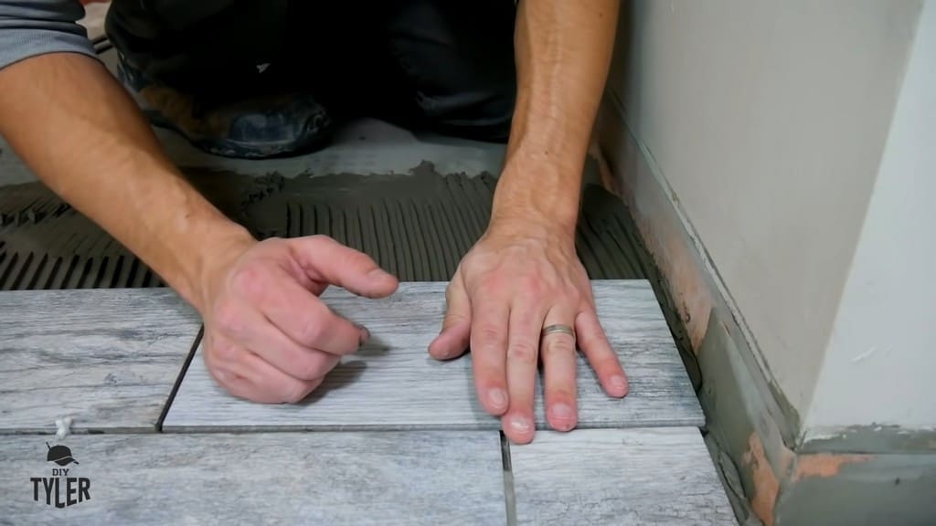 man demonstrating gap between DIY tiling and bathroom wall