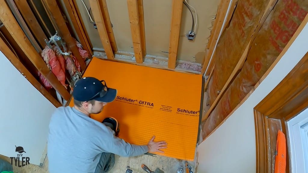 man installing underlayment to bathroom