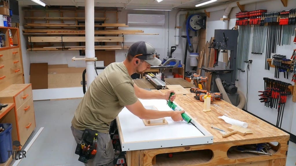 man applying silicone caulk to melamine mold