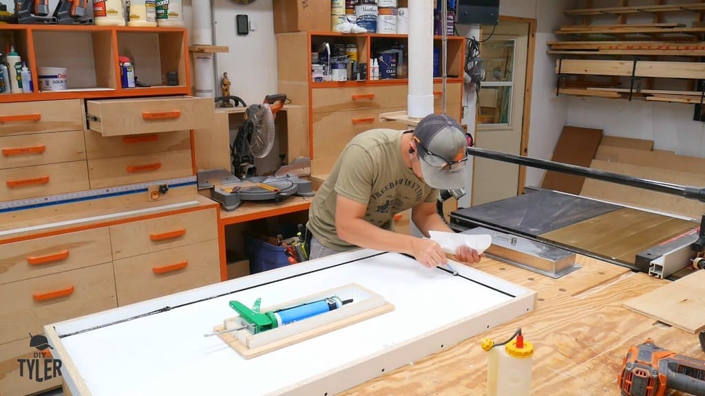 man smoothing out silicone caulk in melamine mold