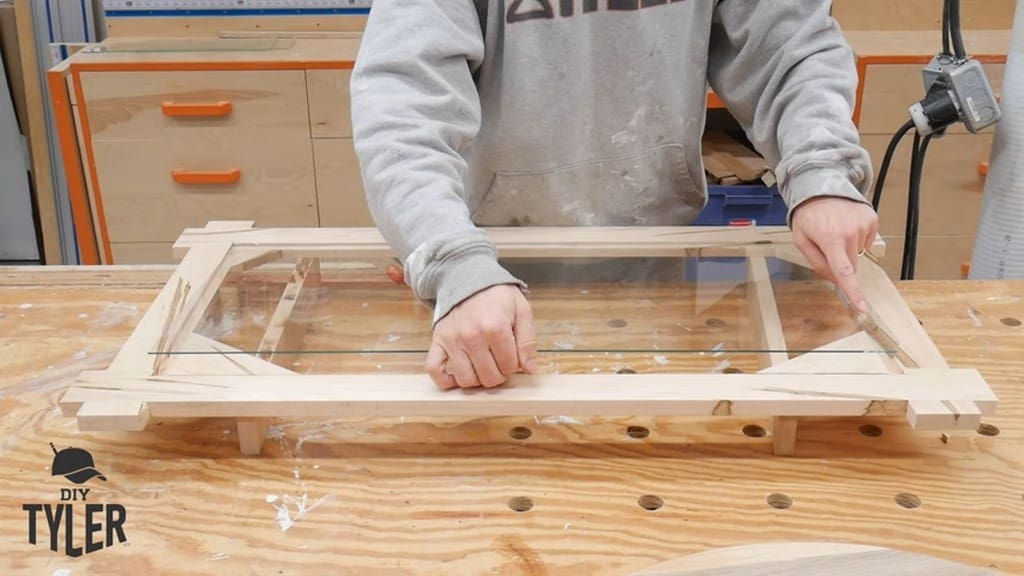 man demonstrating crack in glass sheet for square picture frame