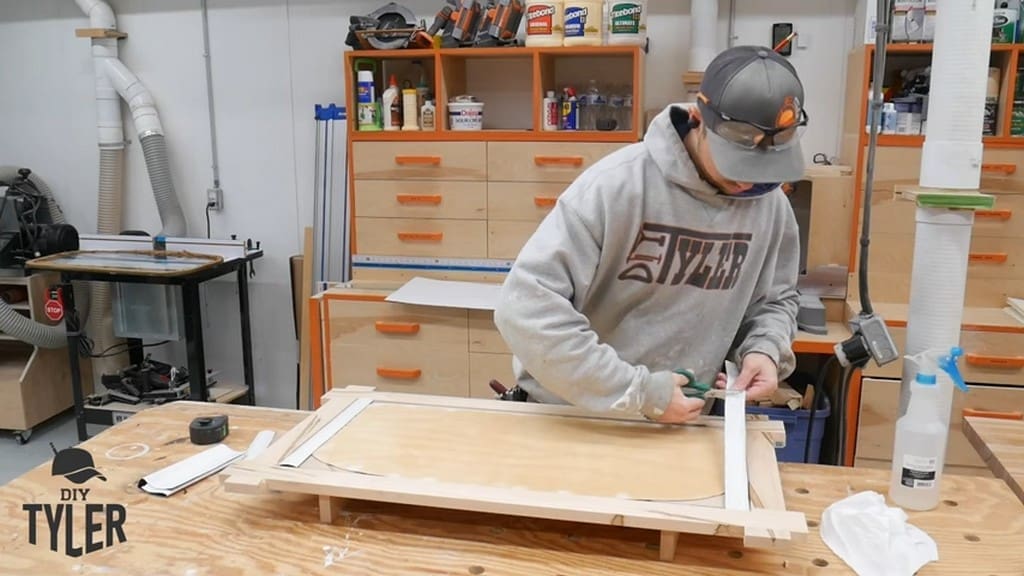 man cutting out felt for backing of square picture frame