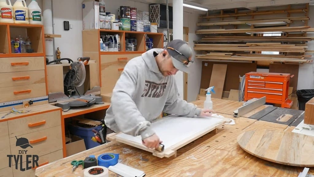 man applying T-rex Tape with roller to backing board for square picture frame