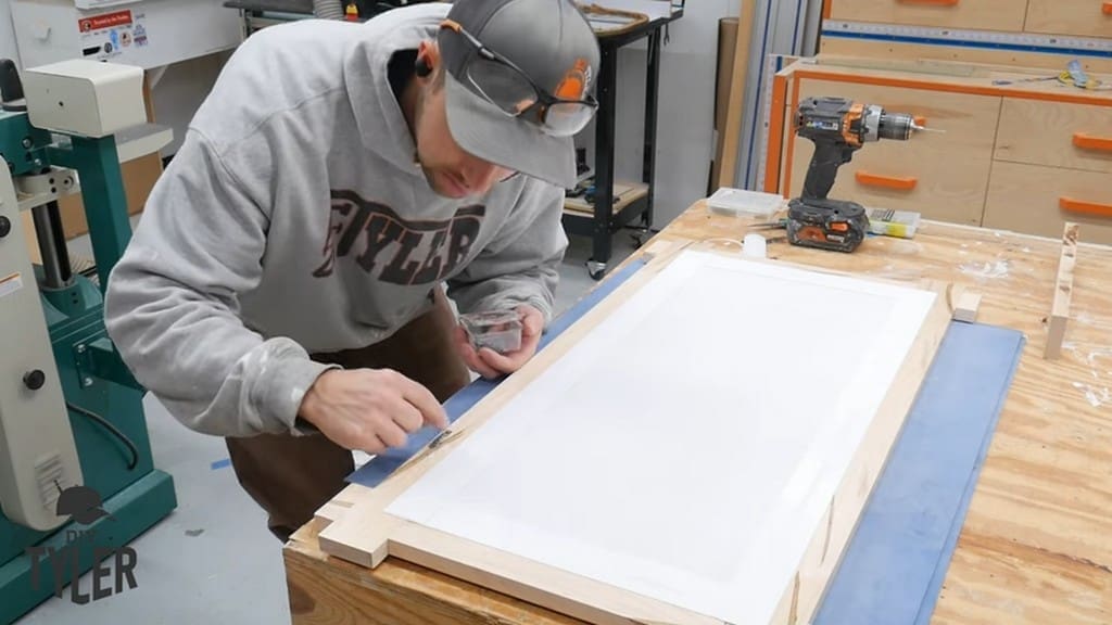 man pointing to sawtooth hangers for square picture frame
