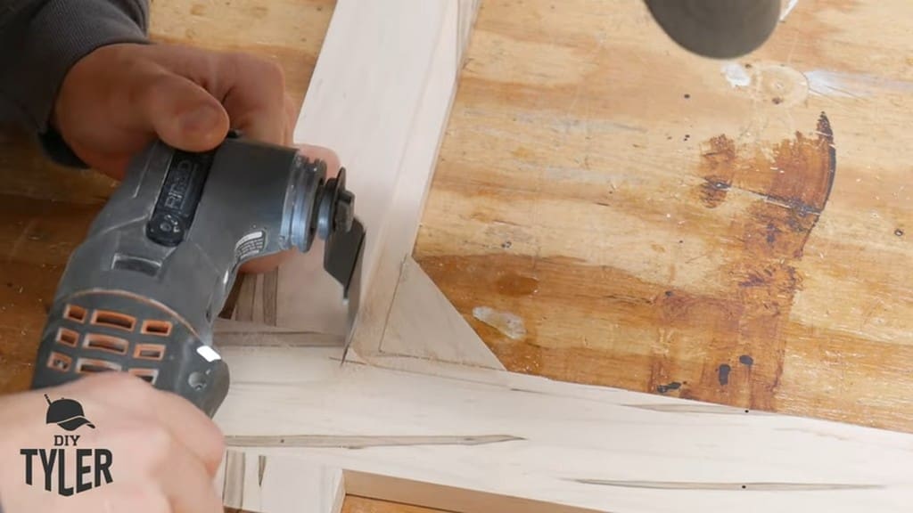 man using multitool to cut out angled piece of square picture frame