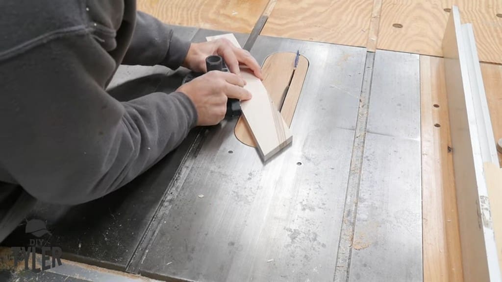 man running angled corner piece through table saw