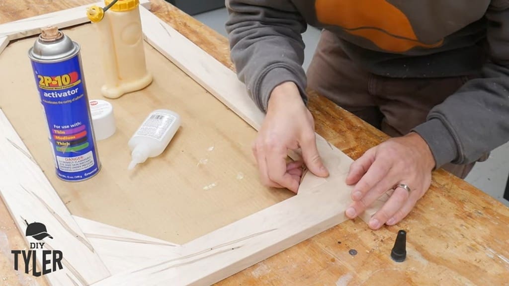 man fastening glued corner piece to square picture frame