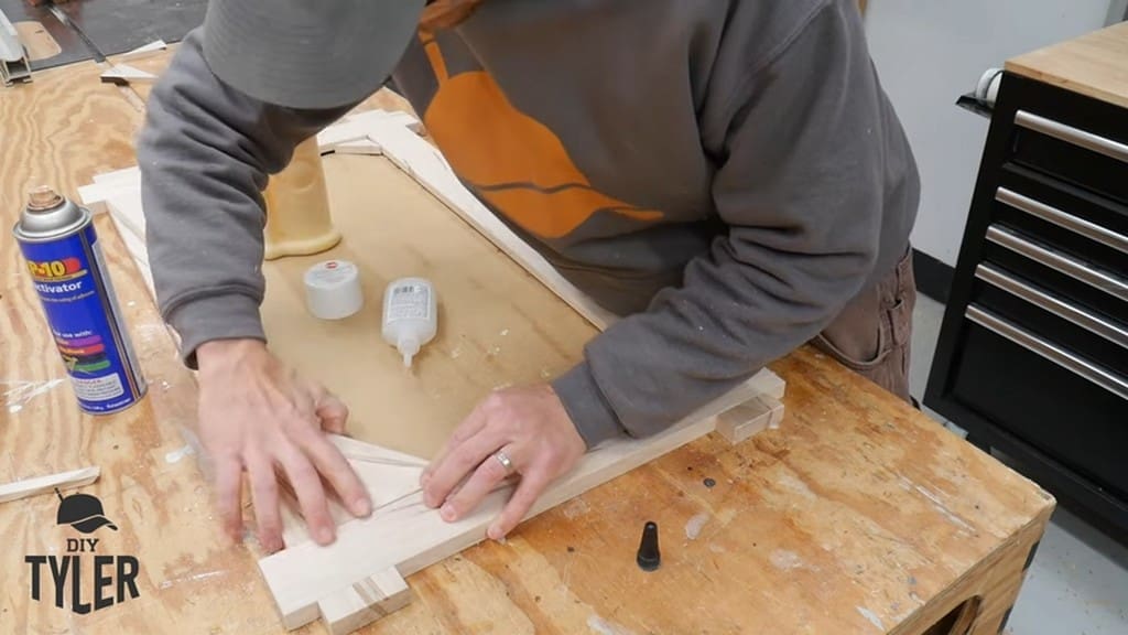 man fastening glued corner piece to square picture frame