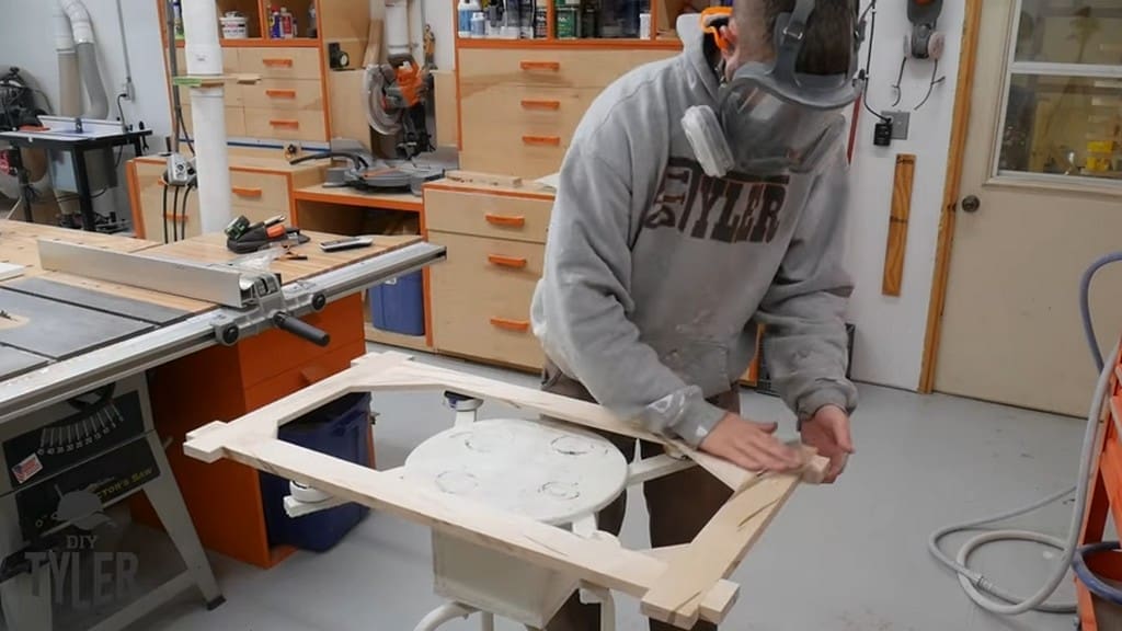 man wiping down square picture frame after applying finish