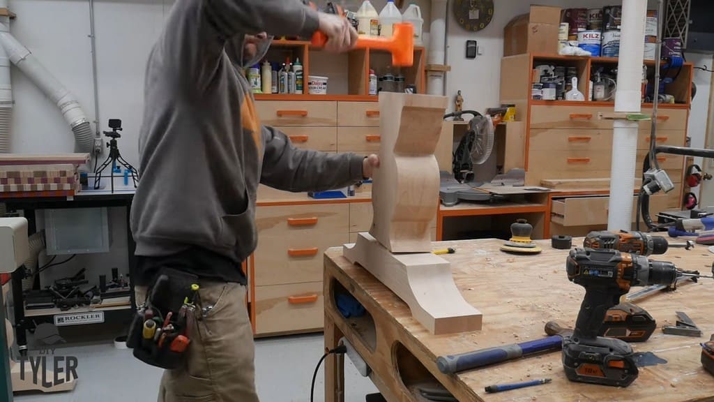 man using mallet to attach vertical and base pedestal pieces
