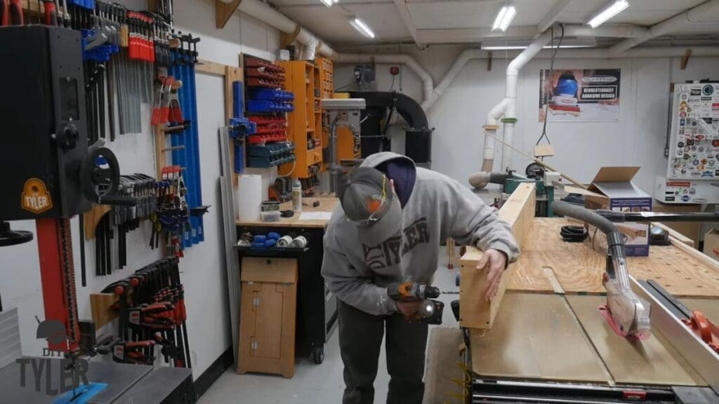 man drilling inlet hole into bottom of steam box for steam bending wood